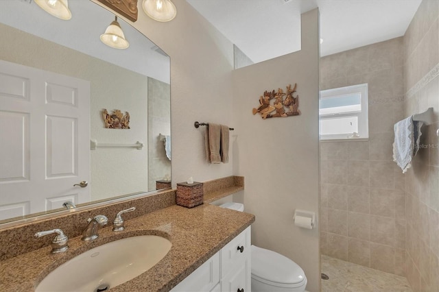 bathroom with vanity, toilet, and a tile shower