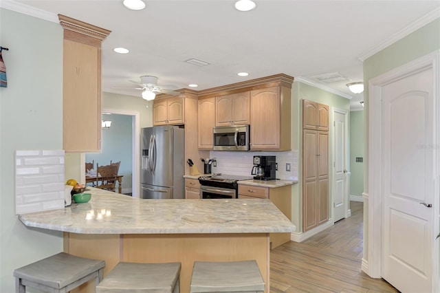 kitchen featuring light brown cabinetry, a breakfast bar, kitchen peninsula, and stainless steel appliances