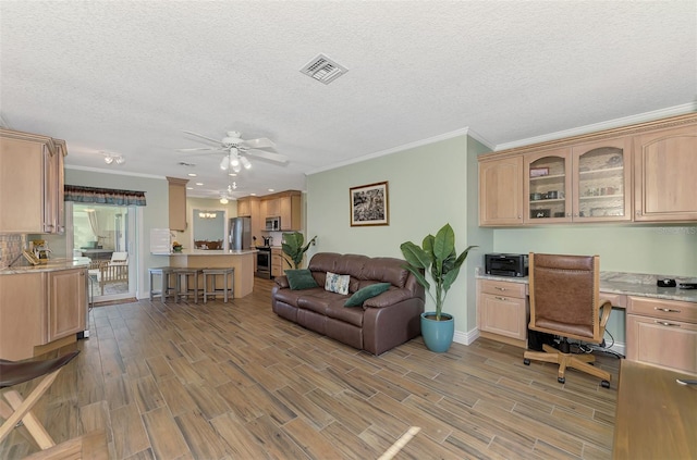 home office with ceiling fan, crown molding, a textured ceiling, and built in desk