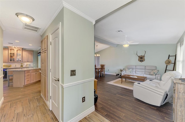 living room featuring lofted ceiling with beams, wood-type flooring, ornamental molding, ceiling fan with notable chandelier, and sink