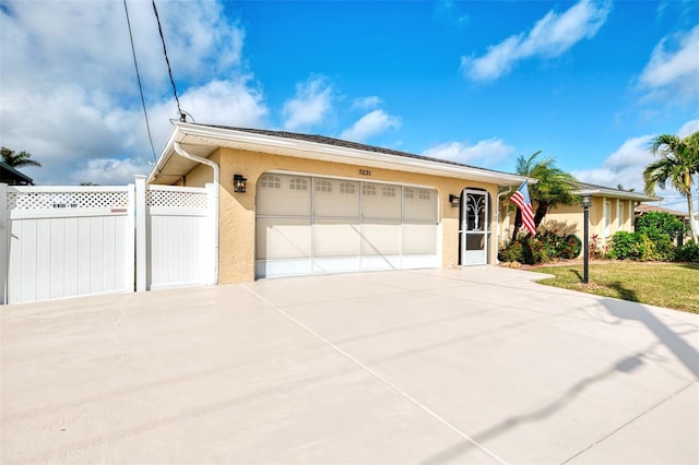 view of front facade featuring stucco siding, fence, concrete driveway, and an attached garage