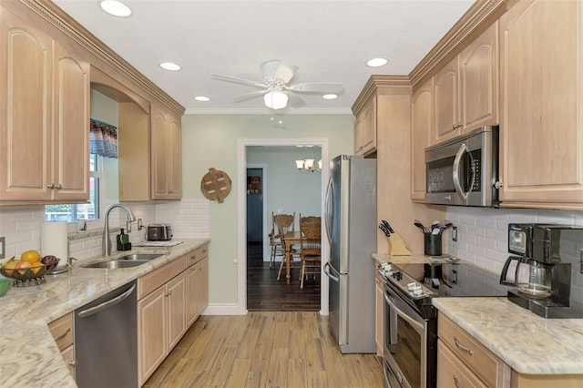 kitchen with light stone countertops, light wood-style flooring, stainless steel appliances, backsplash, and a sink