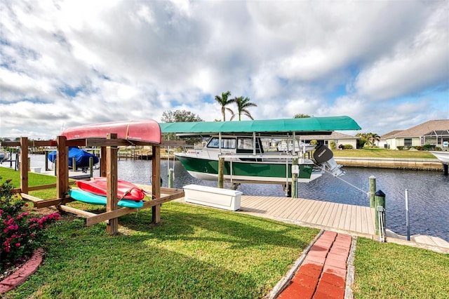 dock area with boat lift, a water view, and a lawn
