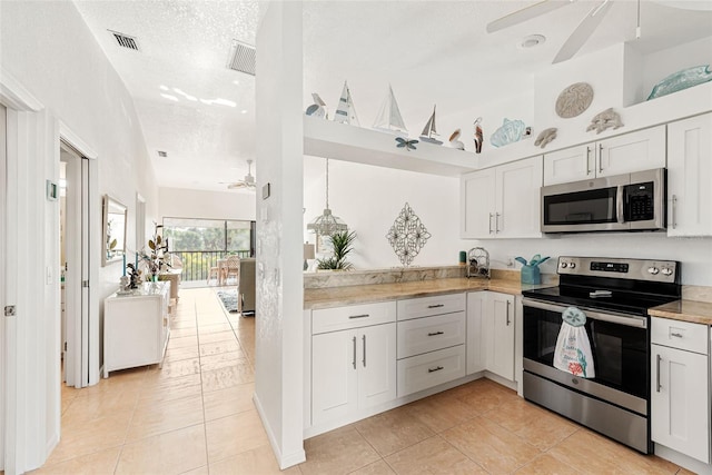 kitchen with ceiling fan, light tile patterned floors, appliances with stainless steel finishes, a textured ceiling, and white cabinets