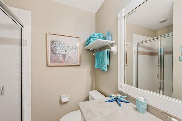 bathroom featuring toilet, a shower with door, and vanity