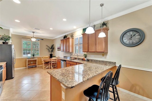 kitchen featuring sink, crown molding, hanging light fixtures, stainless steel appliances, and kitchen peninsula