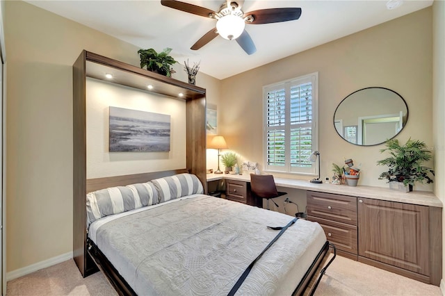 bedroom featuring ceiling fan, built in desk, and light carpet