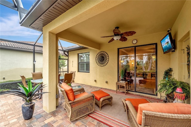 view of patio / terrace featuring ceiling fan and glass enclosure