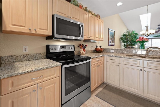 kitchen featuring an inviting chandelier, appliances with stainless steel finishes, light tile patterned flooring, light stone counters, and sink