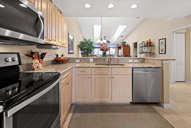 kitchen featuring kitchen peninsula, stainless steel appliances, light brown cabinetry, lofted ceiling with skylight, and a chandelier