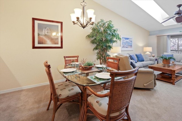 carpeted dining space with vaulted ceiling with skylight and ceiling fan with notable chandelier