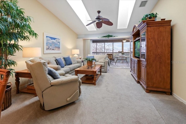 carpeted living room with ceiling fan and lofted ceiling with skylight