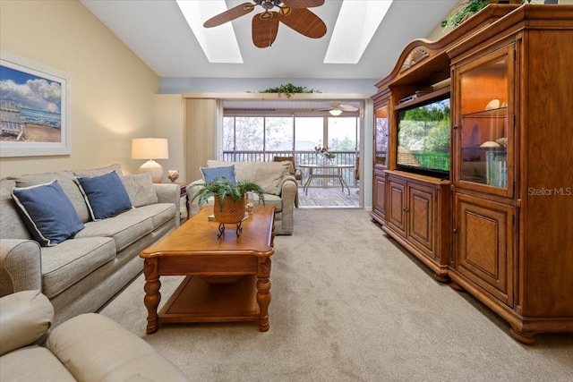 living room featuring ceiling fan, vaulted ceiling with skylight, and light colored carpet