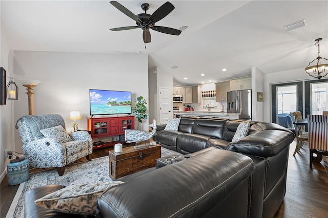 living room with vaulted ceiling, dark hardwood / wood-style flooring, and ceiling fan with notable chandelier