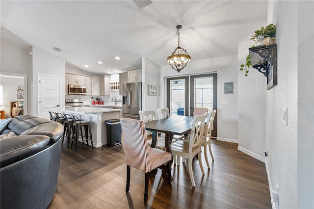 dining area featuring vaulted ceiling, dark hardwood / wood-style floors, sink, and an inviting chandelier