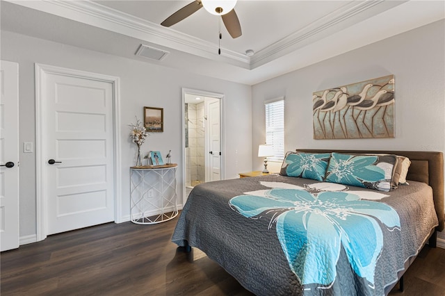 bedroom with ensuite bath, dark wood-type flooring, ceiling fan, a tray ceiling, and ornamental molding