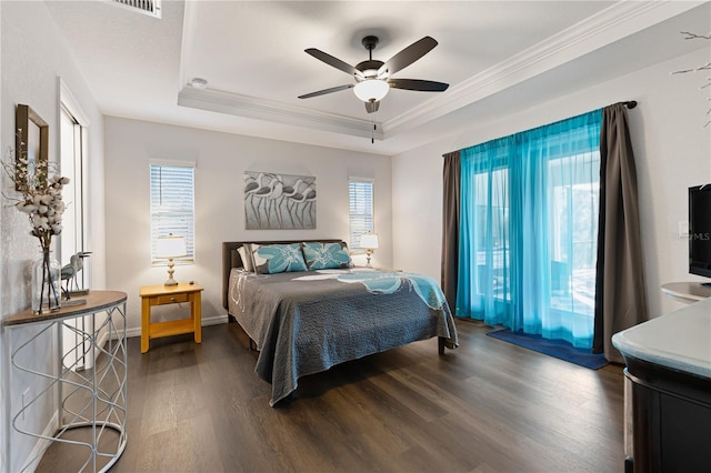 bedroom featuring a raised ceiling, crown molding, dark hardwood / wood-style floors, and ceiling fan