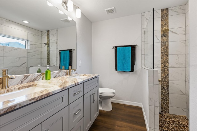 bathroom with tiled shower, wood-type flooring, toilet, and vanity