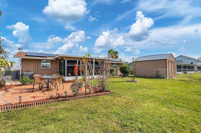 rear view of property with a patio, central air condition unit, solar panels, and a lawn