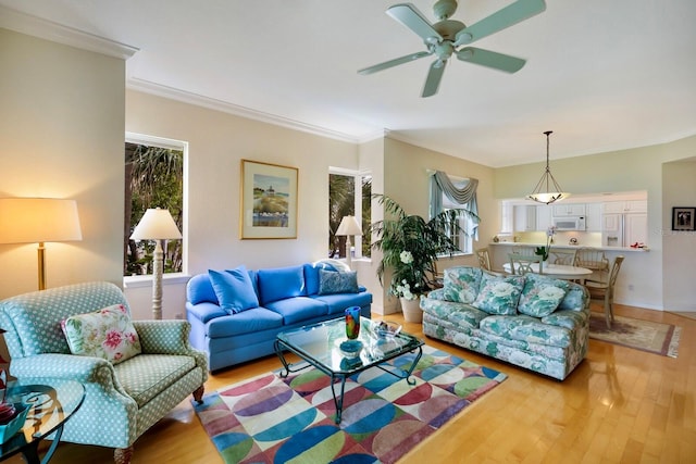 living room with crown molding, light hardwood / wood-style floors, and ceiling fan