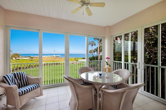 sunroom featuring ceiling fan and a water view