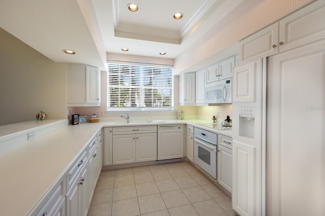 kitchen with a raised ceiling, white cabinets, light tile patterned flooring, white appliances, and ornamental molding