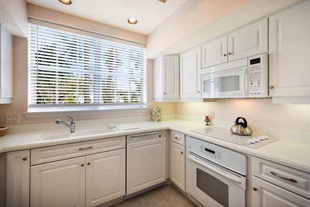 kitchen with sink, white appliances, white cabinetry, and light tile patterned floors