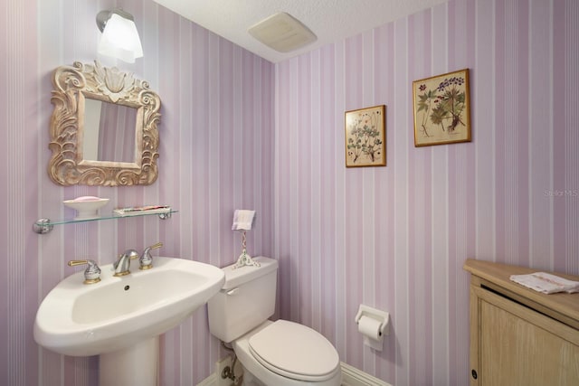 bathroom with sink, a textured ceiling, and toilet