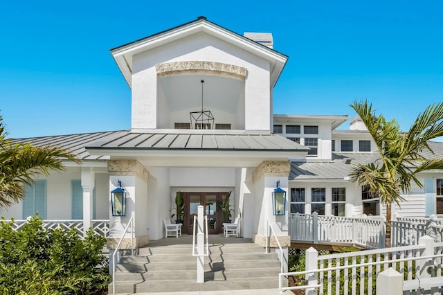 property entrance with covered porch and french doors