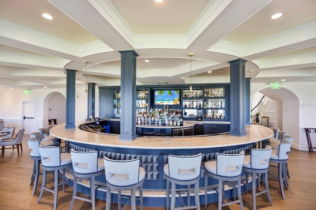 bar featuring wood-type flooring and decorative columns