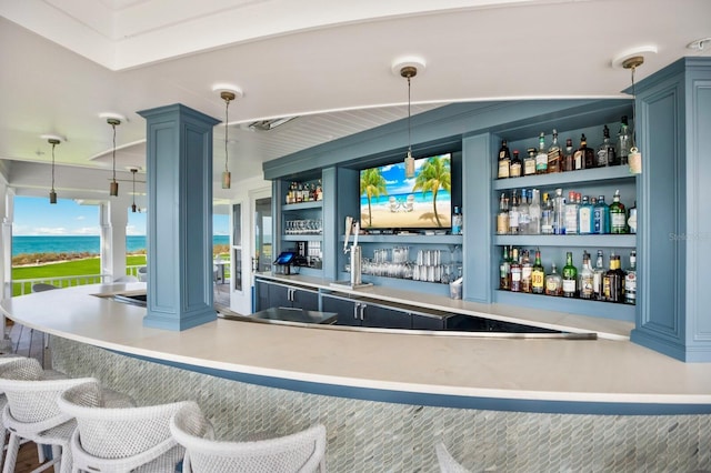 bar featuring blue cabinetry, a water view, and hanging light fixtures