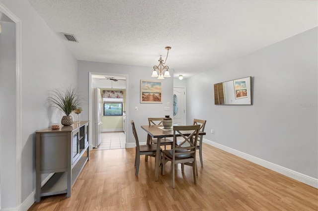 dining room featuring a notable chandelier, a textured ceiling, and light hardwood / wood-style floors