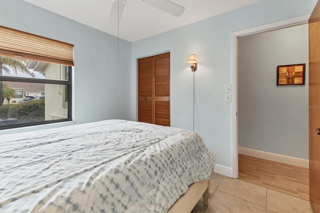 bedroom featuring ceiling fan, a closet, and light tile patterned floors