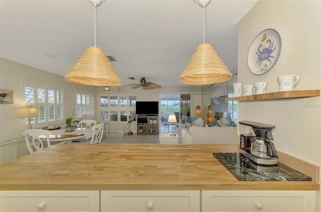 kitchen with ceiling fan, white cabinets, decorative light fixtures, and butcher block counters