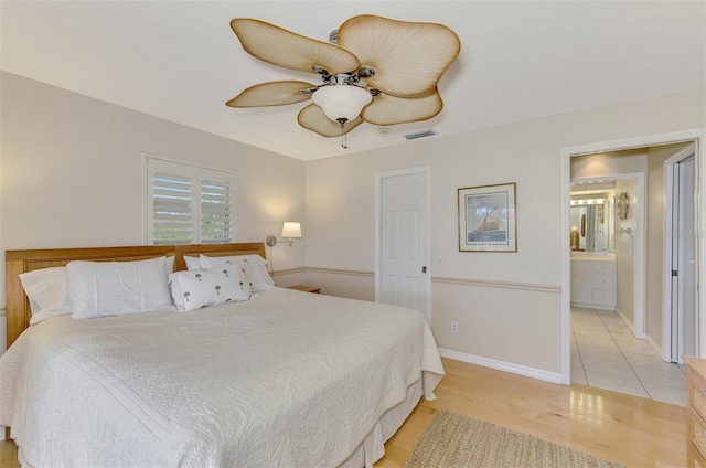 bedroom featuring ceiling fan, ensuite bath, and light wood-type flooring