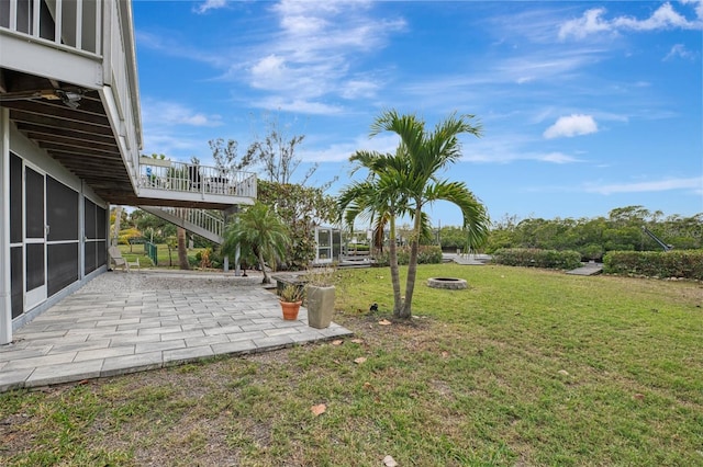 view of yard with a patio area, a sunroom, and a fire pit