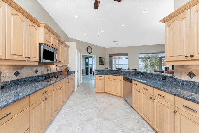 kitchen with appliances with stainless steel finishes, light brown cabinetry, and decorative light fixtures