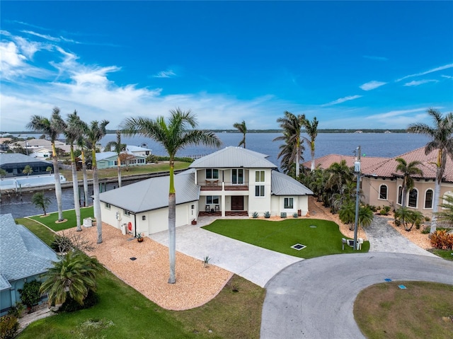 view of front of house featuring a balcony, a front yard, a garage, and a water view