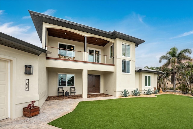 rear view of property featuring a yard and a balcony