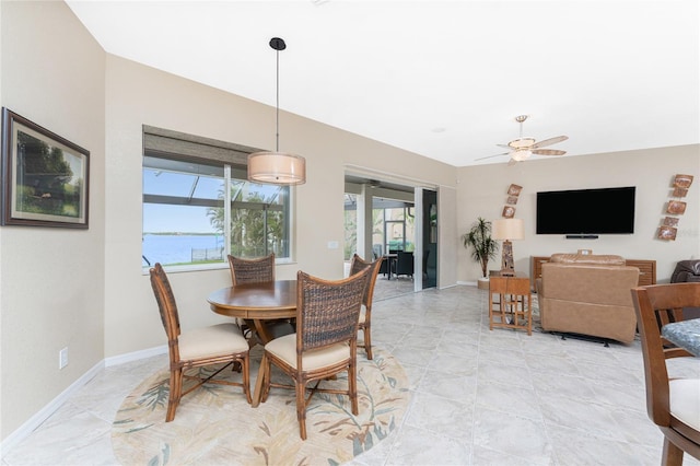 dining space with a water view and ceiling fan