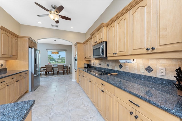 kitchen with decorative light fixtures, light brown cabinets, appliances with stainless steel finishes, and dark stone counters