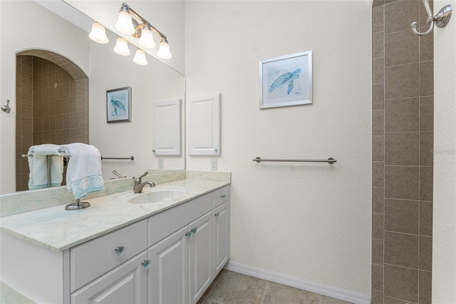 bathroom featuring tiled shower, vanity, and tile patterned flooring