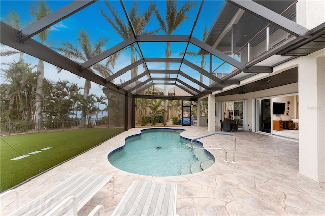 view of swimming pool featuring a lanai, a lawn, and a patio