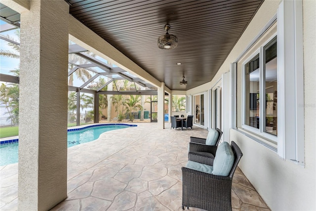 view of pool featuring glass enclosure, a patio area, and ceiling fan