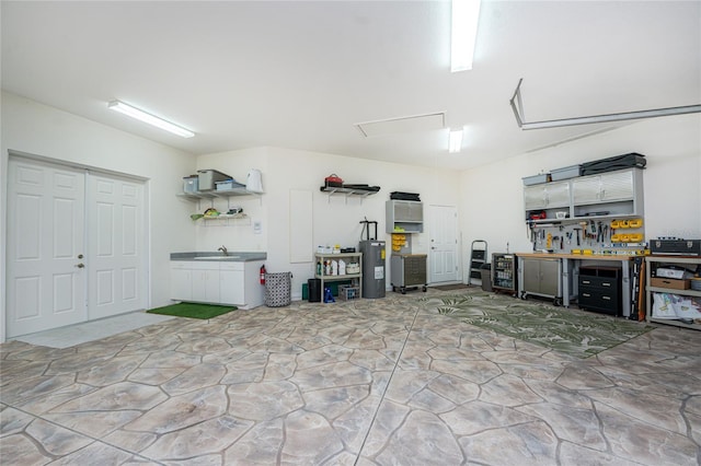 garage with electric water heater, a workshop area, and sink