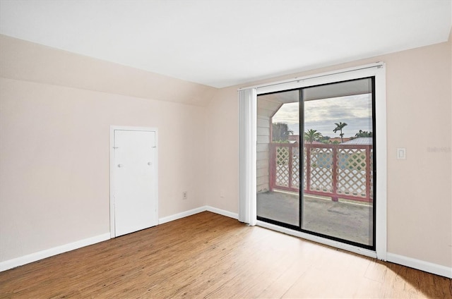 unfurnished room featuring vaulted ceiling, a healthy amount of sunlight, and light hardwood / wood-style flooring