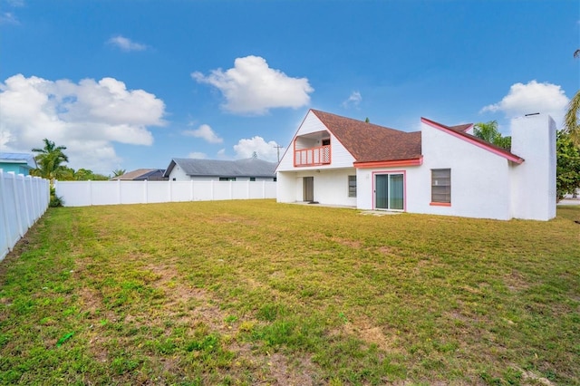 back of house with a lawn and a balcony