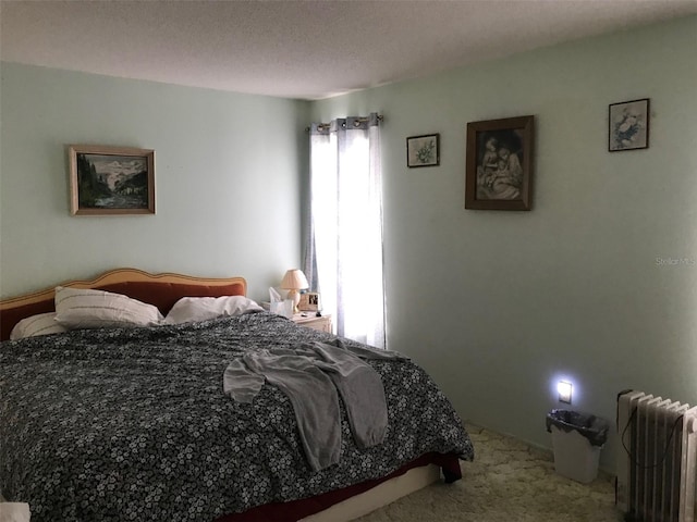 carpeted bedroom with a textured ceiling and radiator heating unit