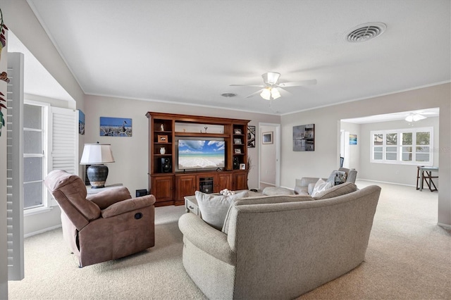 carpeted living room with ornamental molding and ceiling fan