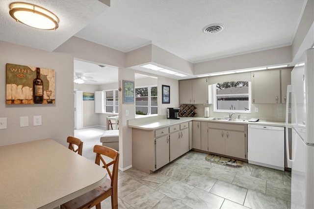 kitchen with sink, ceiling fan, white dishwasher, a textured ceiling, and decorative backsplash